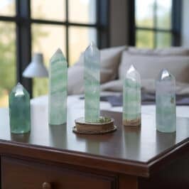 Green Fluorite Towers On A Bedroom Table. Green gemstone crystal decor for jewelry display and interior styling.