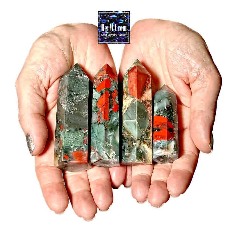 HerMJ - Bloodstone Tower Crystals - Held In Hands. Vibrant gemstone healing crystals with green, red, and black hues held in a person's hands, showcasing natural gemstone decor for wellness and spiritual growth.