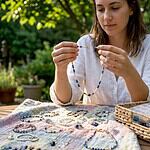 Woman examining unique handmade gemstone jewelry at wooden table