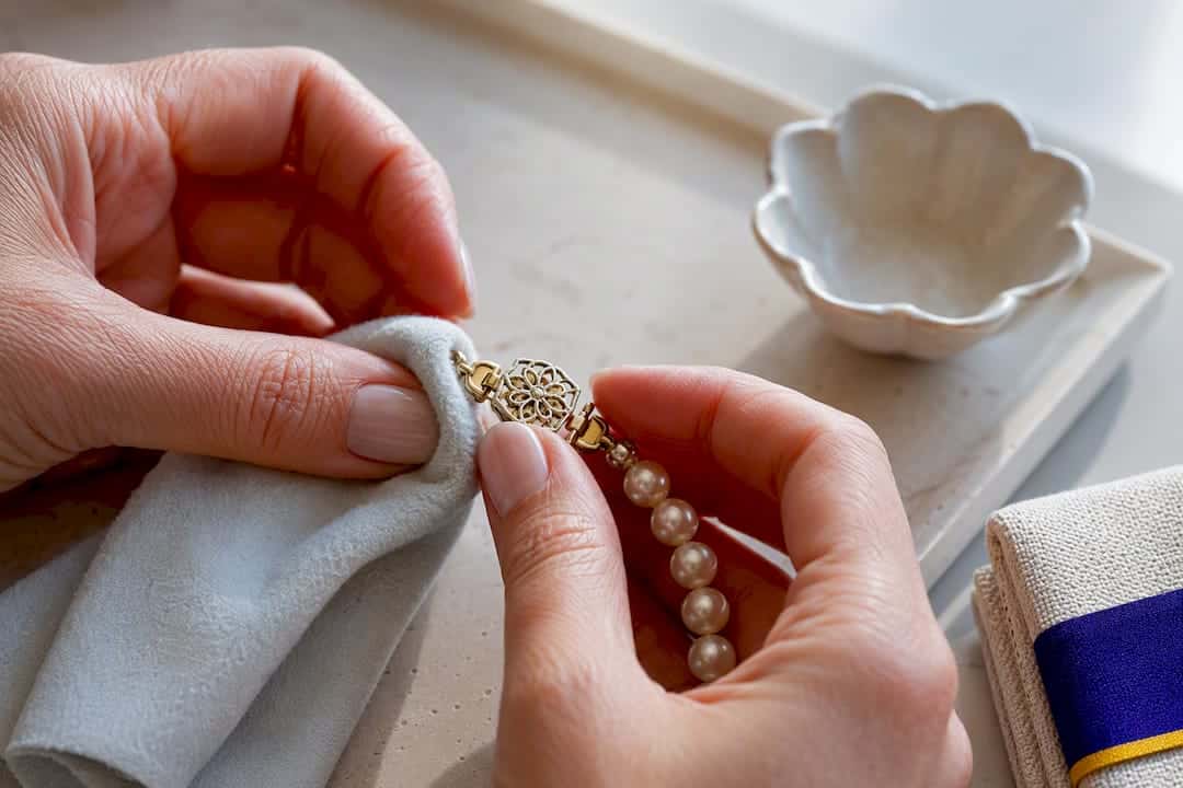 Avoid Losing Pearls: Match Pearl Necklace Clasps to Strand Weight Hands wiping a pearl necklace clasp
